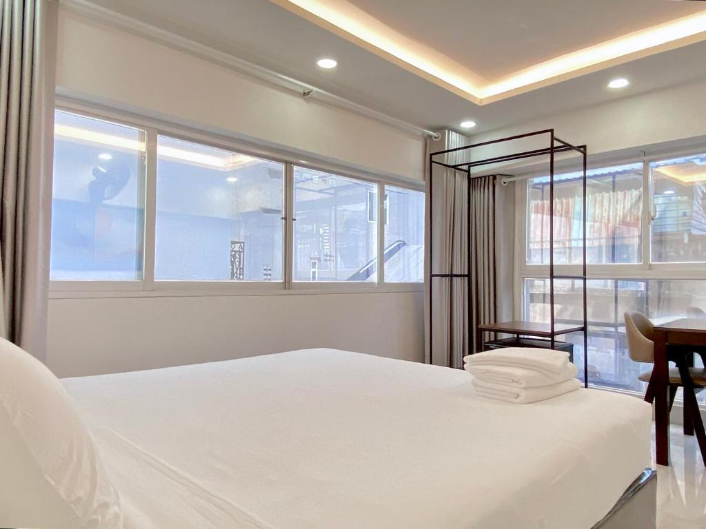1 dormitorio con 1 cama blanca, escritorio y ventanas en Haha House en Ho Chi Minh