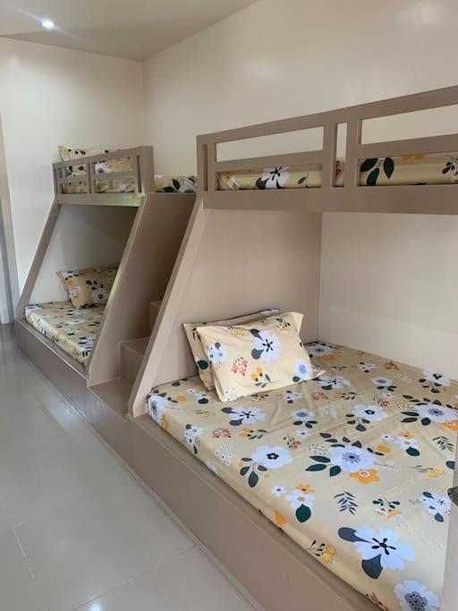 a bedroom with two bunk beds with flowers on the sheets at PMPJ Cabin in Lipa