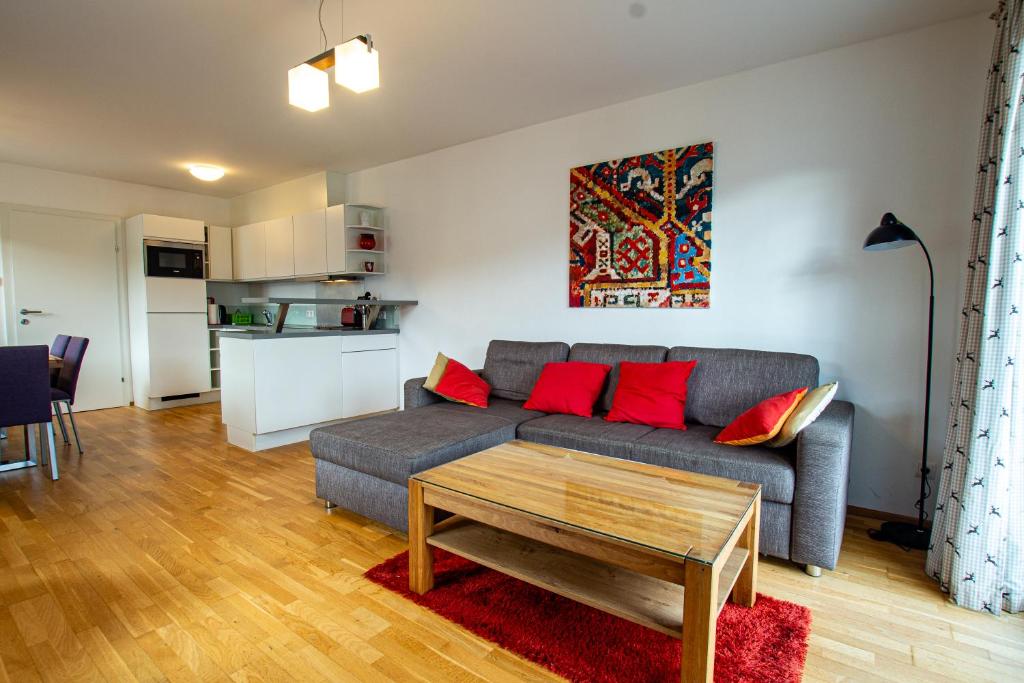 - un salon avec un canapé gris et des oreillers rouges dans l'établissement Pine Residence Zell am See - Steinbock Lodges, à Zell am See
