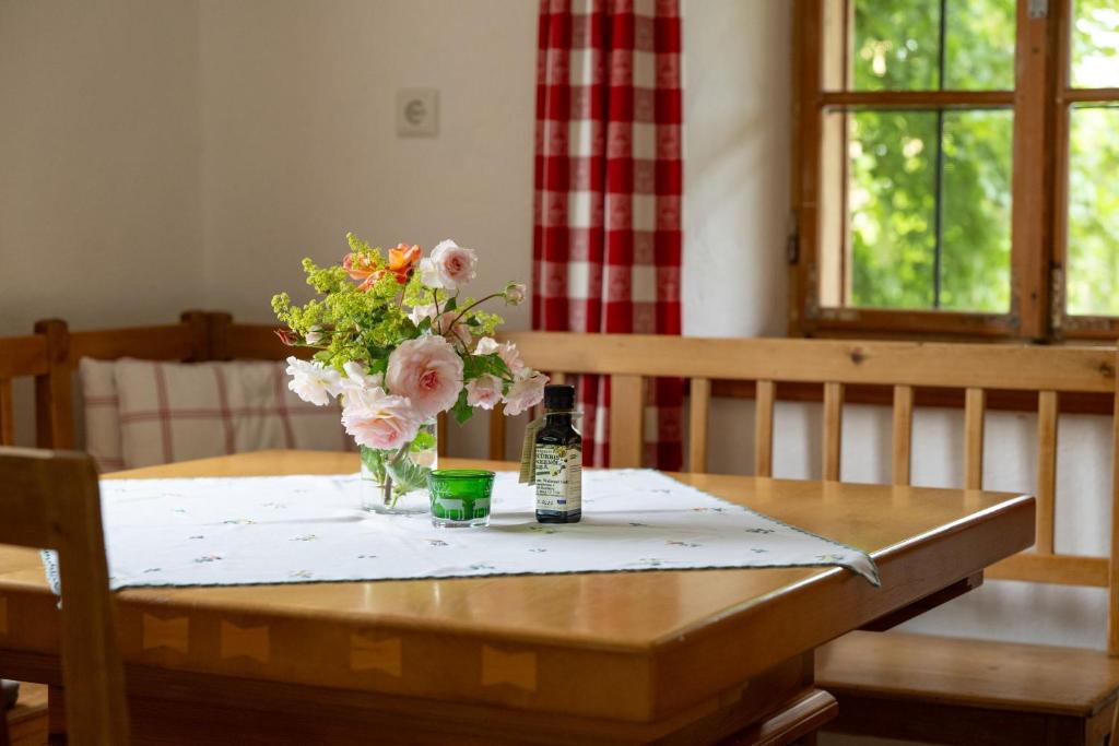 a bottle of wine and a vase of flowers on a table at Landlust-Ferienhaus Am Rosenhof in Hartberg