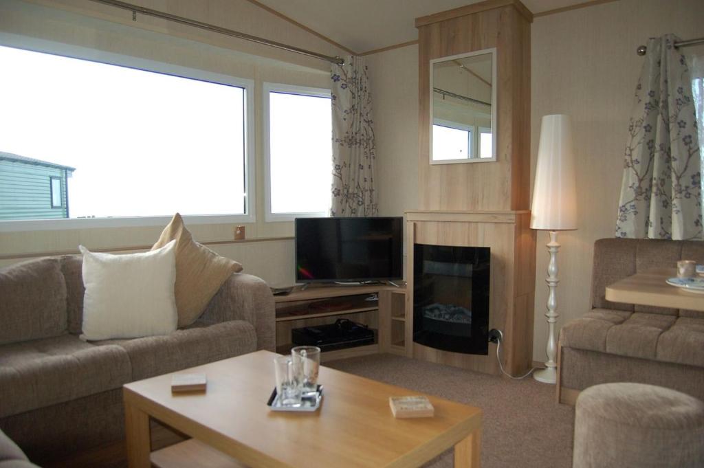 a living room with a couch and a tv at Caravan 20 Neptune Caravan Park in Tywyn