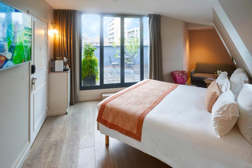 a hotel room with a large bed and a balcony at Hôtel Vic Eiffel in Paris