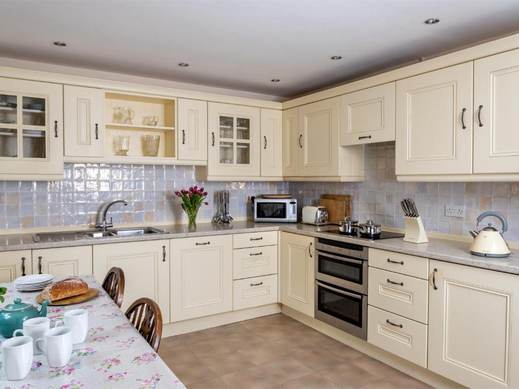 a kitchen with white cabinets and a table at 3 Bed in Hay-on-Wye BN345 in Hay-on-Wye