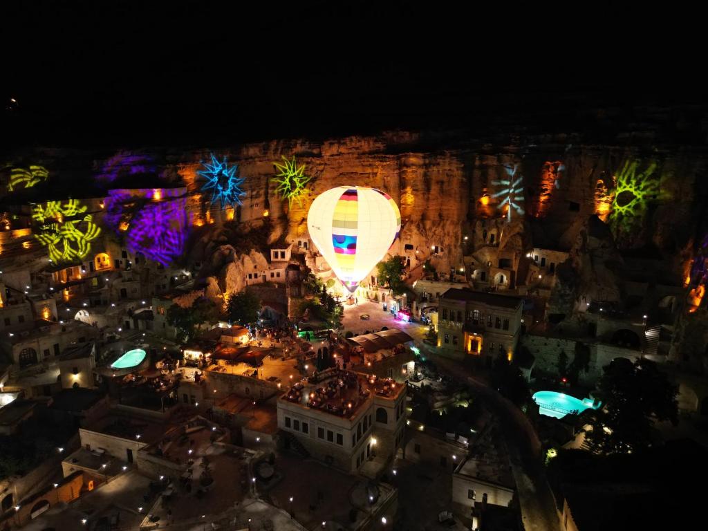 un globo de aire caliente volando sobre una ciudad por la noche en Yunak Evleri Cappadocia, en Ürgüp