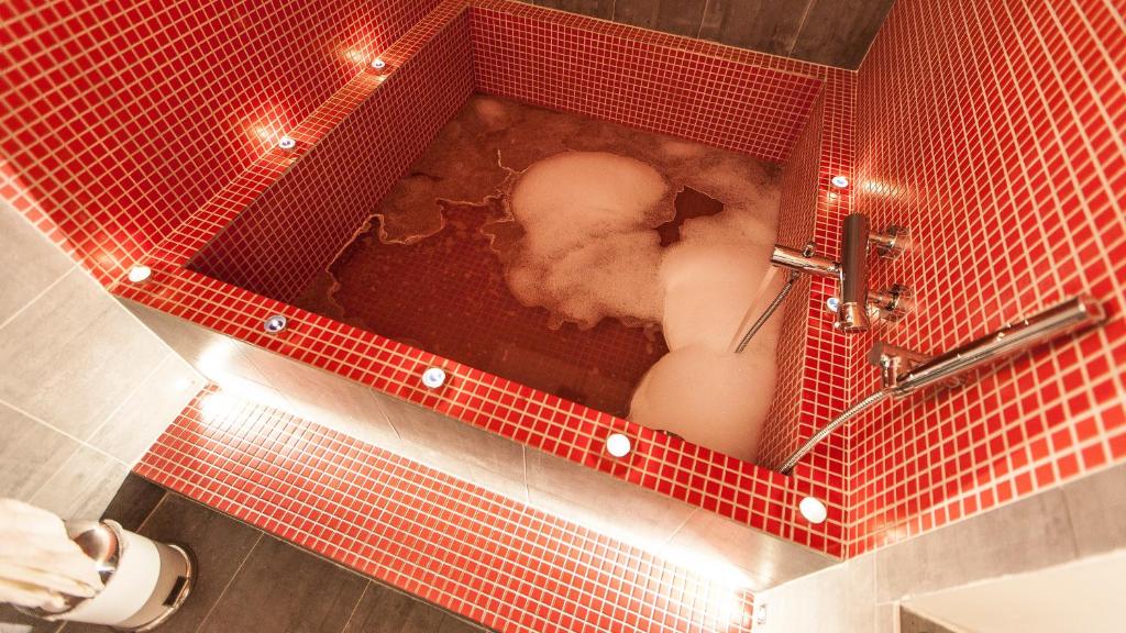 a red tiled bathroom with a red tub with a person in it at Ostilia Loft in Rome