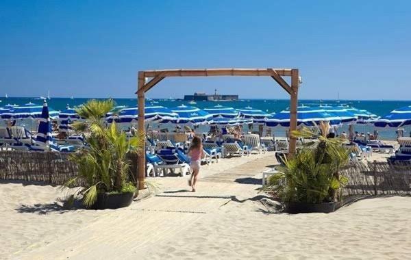 une femme se promenant le long d'une plage avec des chaises et des parasols dans l'établissement Appartement 3 Pièces 5 couchages Plage Richelieu CAP D'AGDE, au Cap d'Agde