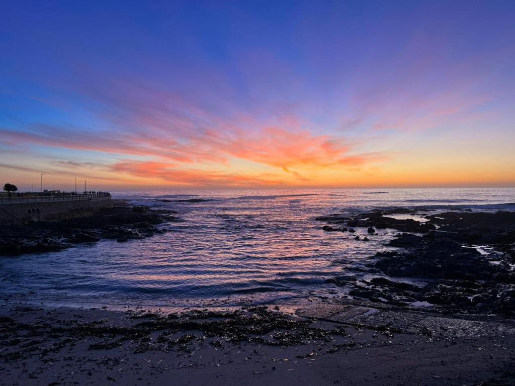 a sunset over a body of water with a pier at Sunset Retreat at Bay Point in Cape Town