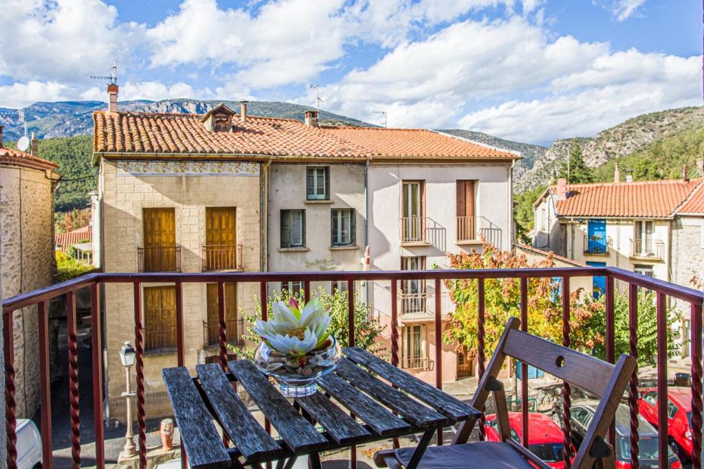 une table en bois sur un balcon avec une maison dans l'établissement Maison de village CorneilladeConflent Pyrnees, à Corneilla-de-Conflent