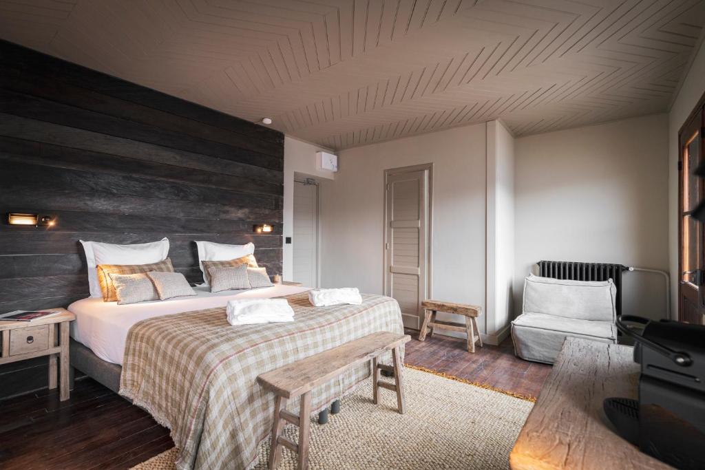 - une chambre avec un grand lit et une chaise dans l'établissement Le Refuge du Grand Hôtel - Altitude 1900 m, à Saint-Chaffrey