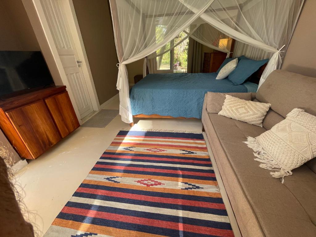 una camera da letto con un letto, un divano e una televisione di Suite de Luxo / Frente Mar / Serra Grande, Bahia (Luzimares) a Serra Grande