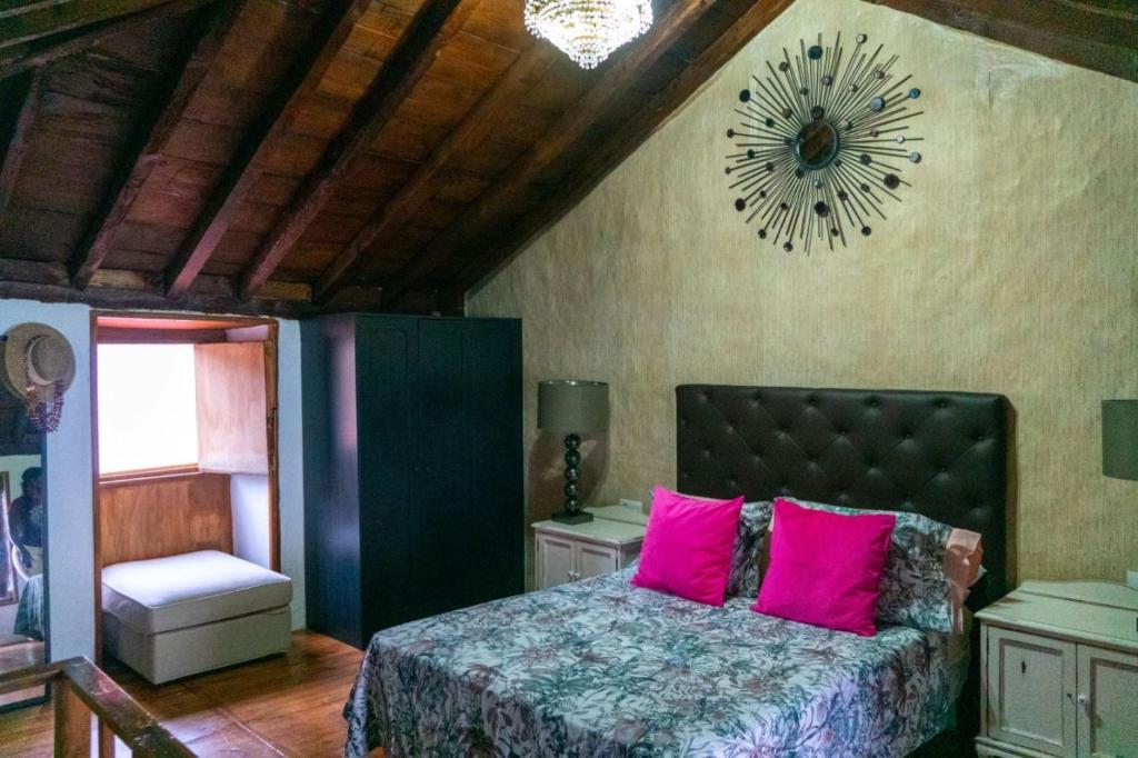ein Schlafzimmer mit einem Bett mit rosa Kissen und einer Uhr in der Unterkunft Casa Lola in Los Realejos