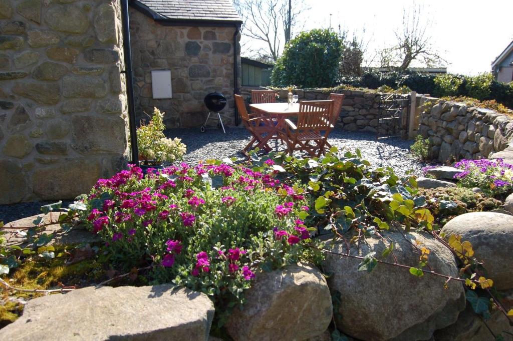 einen Garten mit Blumen, einem Tisch und einer Bank in der Unterkunft Anneddle Cottage in Talybont, near Barmouth in Talybont