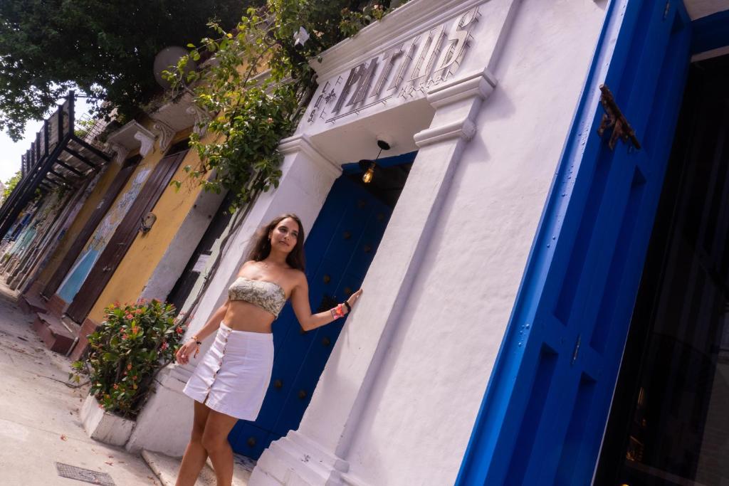 uma mulher em pé em frente a uma porta azul em Los Patios Hostel em Cartagena de Indias