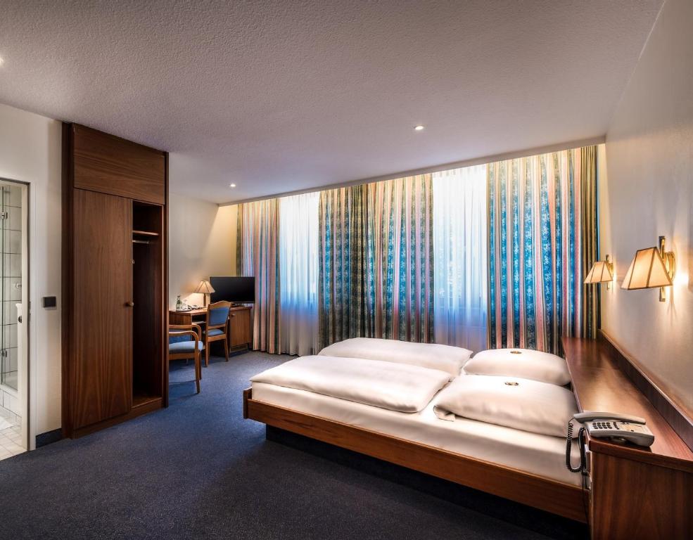 a bedroom with a large bed and a desk at Hotel Alte Wache in Hamburg