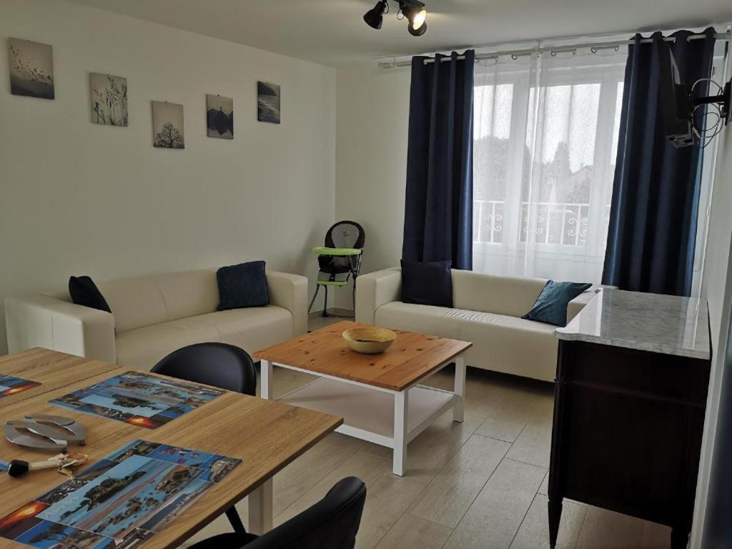 a living room with a couch and a table at APPARTEMENTS- Place Alexandres 4 Vents in Asnelles
