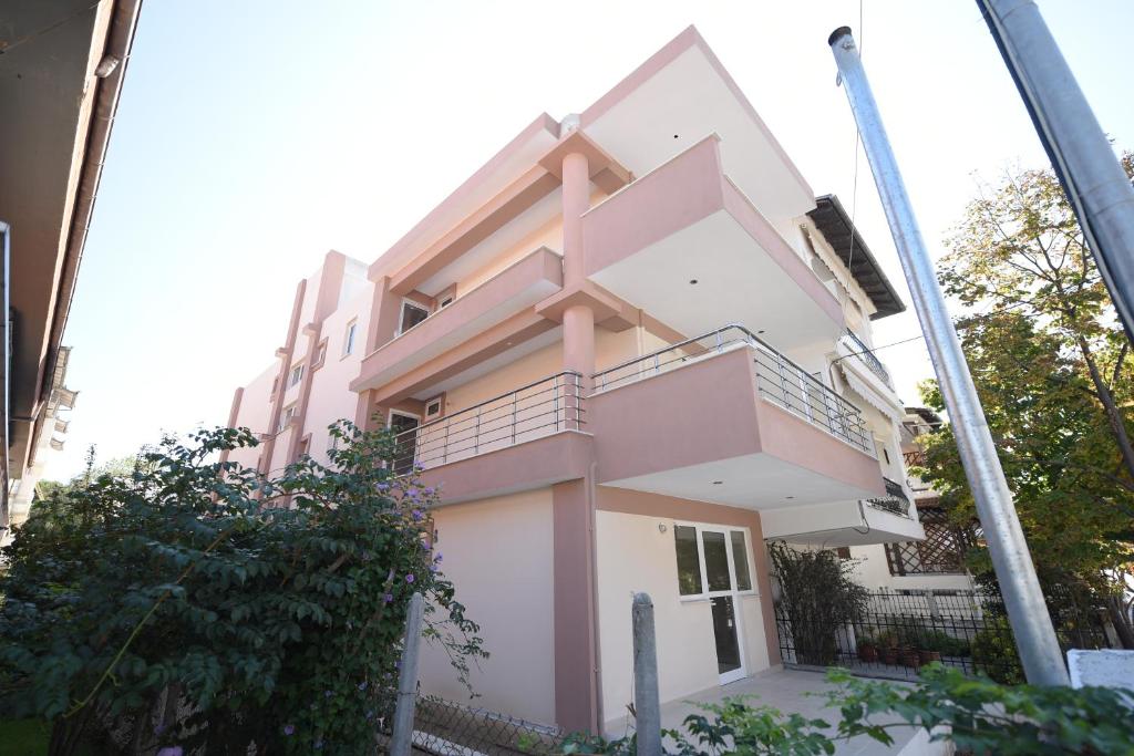 a pink building with a balcony in front of it at Mango in Paralia Katerinis