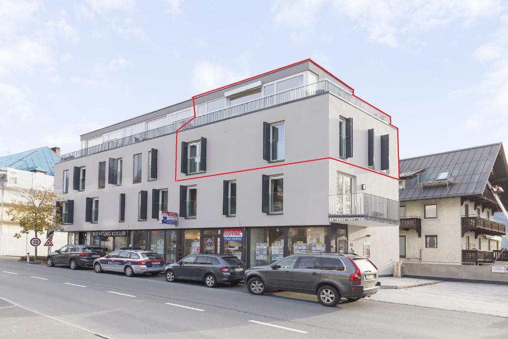 a white building with cars parked in front of it at Apartment O'Hara in Zell am See