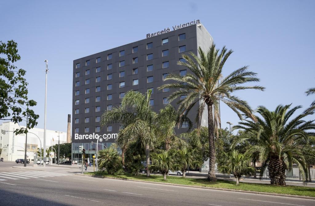 a building with palm trees in front of a street at Barceló Valencia in Valencia