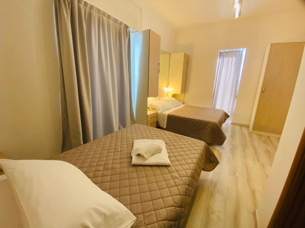 a small room with two beds and a mirror at Hotel Butterfly Wellness & Spa in Rimini