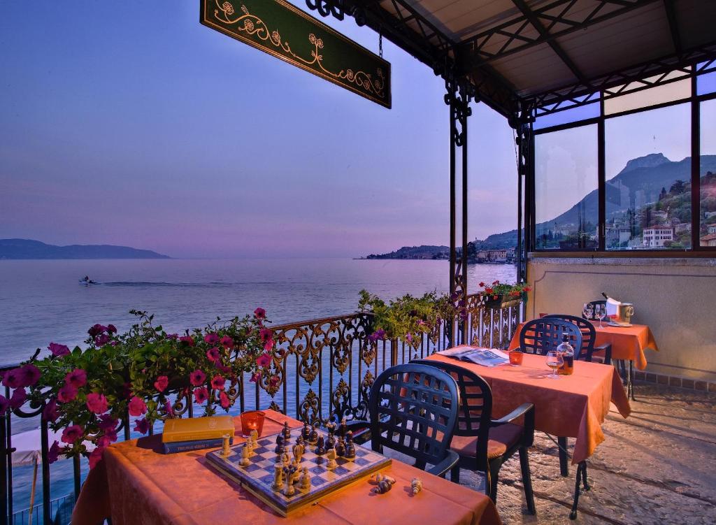 un restaurante con mesas y sillas con el océano en el fondo en Hotel Garnì Riviera, en Gargnano