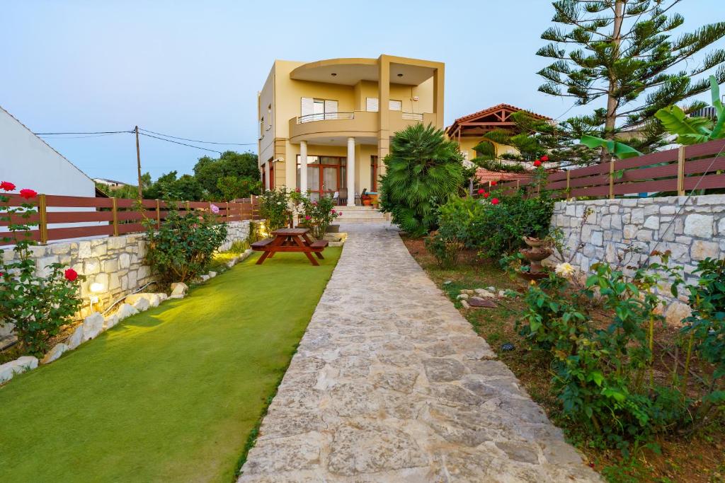 einen Garten mit einem Steinweg, der zu einem Haus führt in der Unterkunft Kelaya Luxury Apartments in Gournes