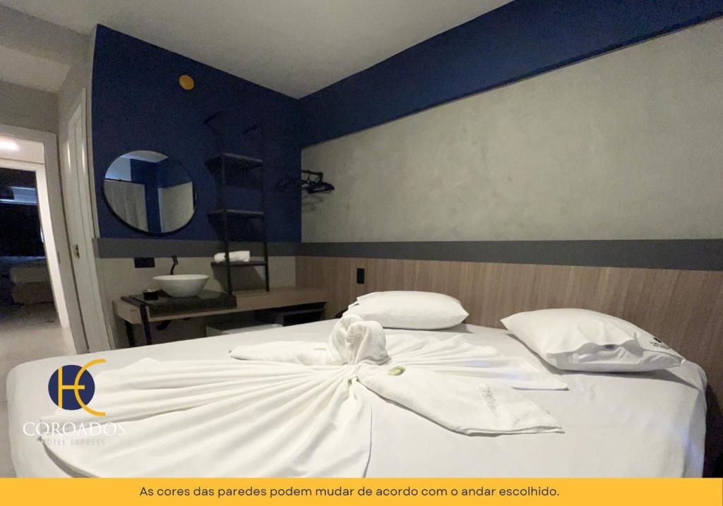 1 cama con sábanas blancas y almohadas en una habitación en Hotel Coroados Foz Express, en Foz do Iguaçu