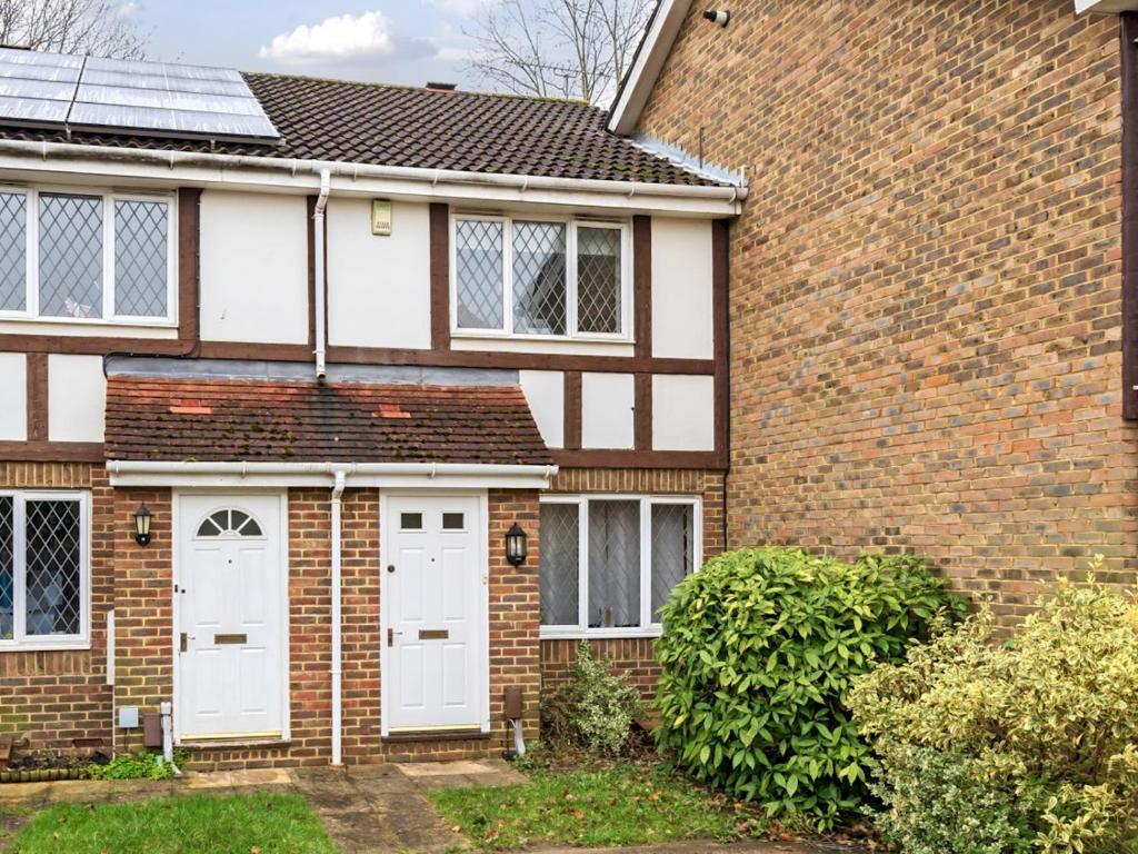 a brick house with white garage doors at Pass the Keys Cosy 2BR Home in Walton in Walton-on-Thames