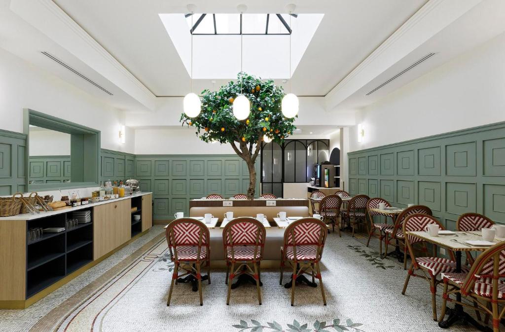 a dining room with a table and chairs and a tree at Timhotel Palais Royal in Paris