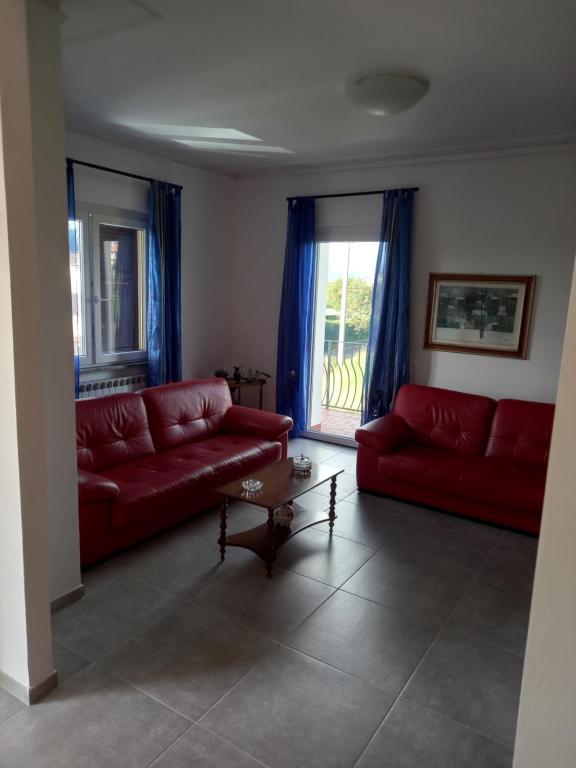 a living room with two red couches and a window at Ca' LUCIANO in Castelnuovo Magra