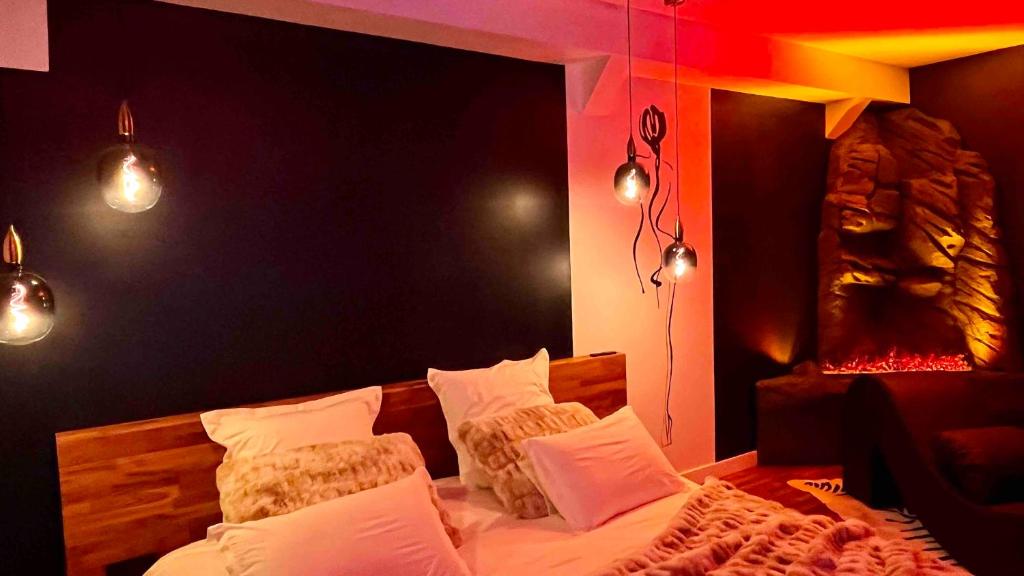 een slaapkamer met een bed met witte kussens en verlichting bij Love Room Cholet Le Double L in Cholet