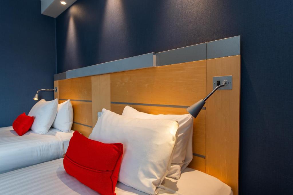 a bedroom with a bed with red and white pillows at Holiday Inn Express Ramsgate – Minster by IHG in Minster