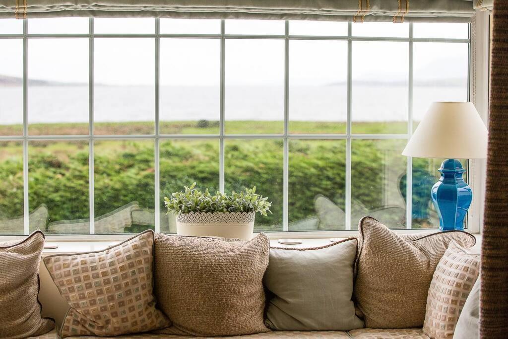 a couch with pillows in front of a large window at Beautiful spacious old schoolhouse with stunning sea views and beach nearby in Port Bannatyne