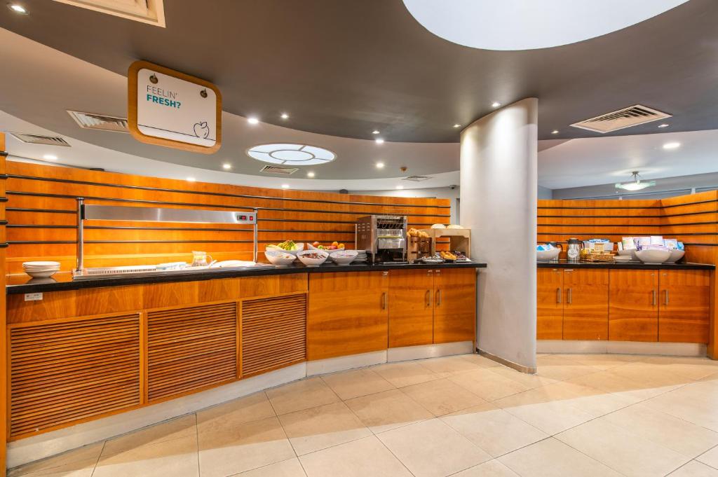 a kitchen with wooden cabinets and a counter in a restaurant at Holiday Inn Express Ramsgate – Minster by IHG in Minster