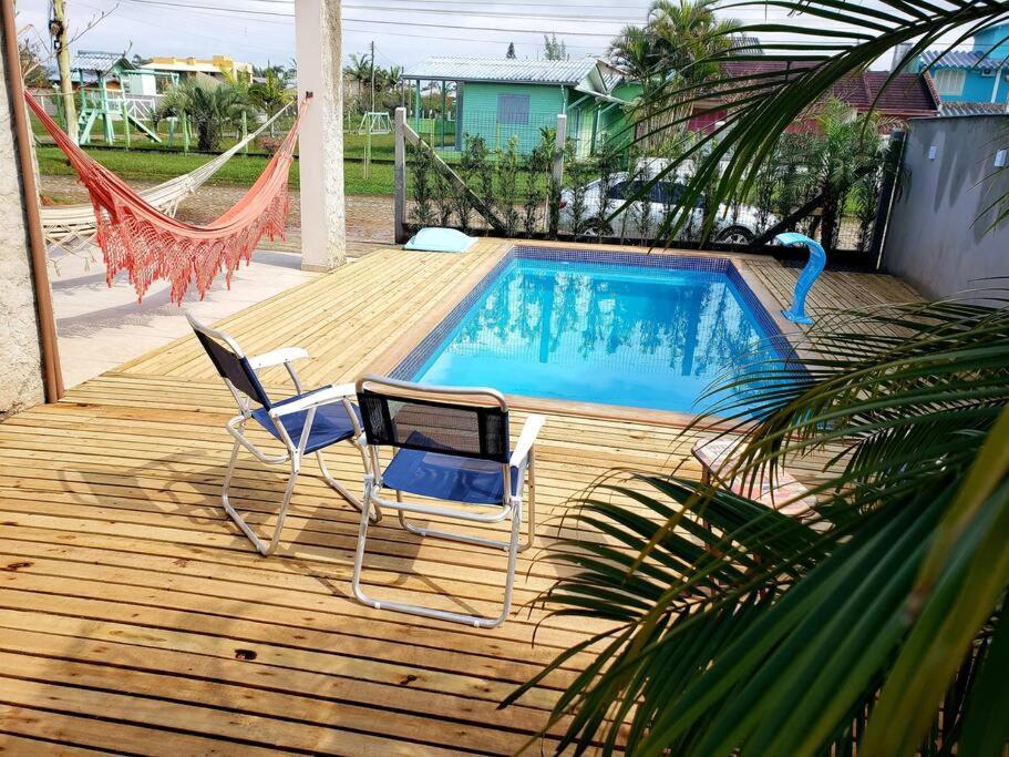 una terraza con 2 sillas y una piscina en Casa com piscina / Na quadra do mar Torres-RS en Torres