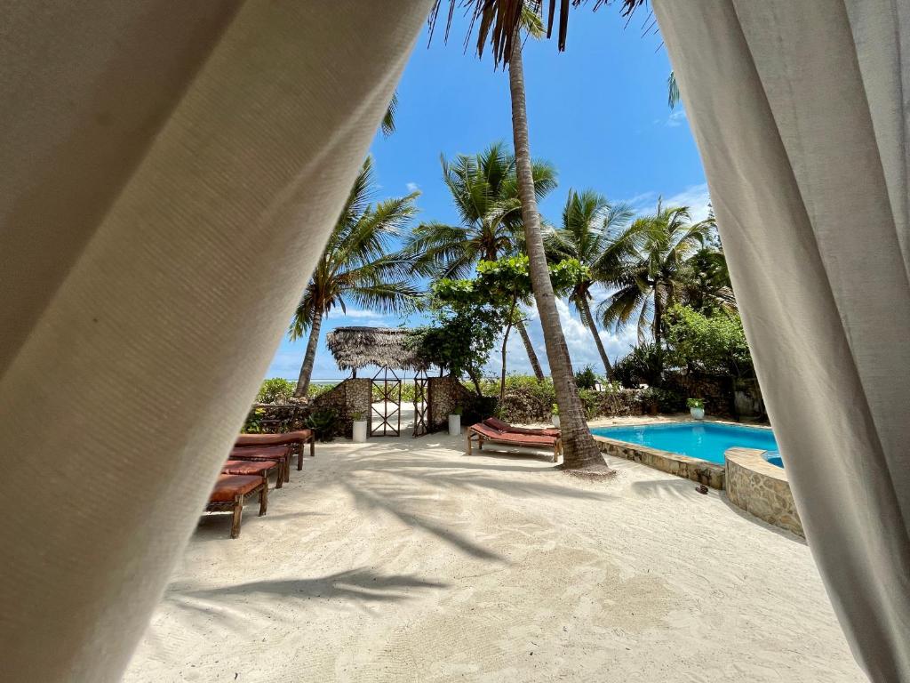 a view of a resort with a pool and palm trees at Villa Kipara - Beachfront with Private Pool in Pwani Mchangani