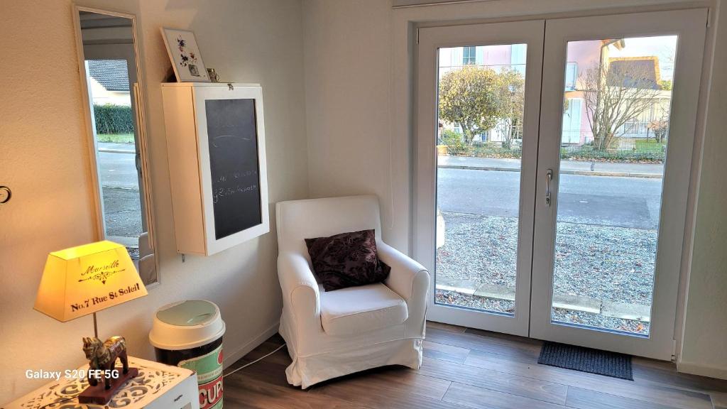 a living room with a white chair and a window at Charmante Waldrandidylle in Kreuzlingen