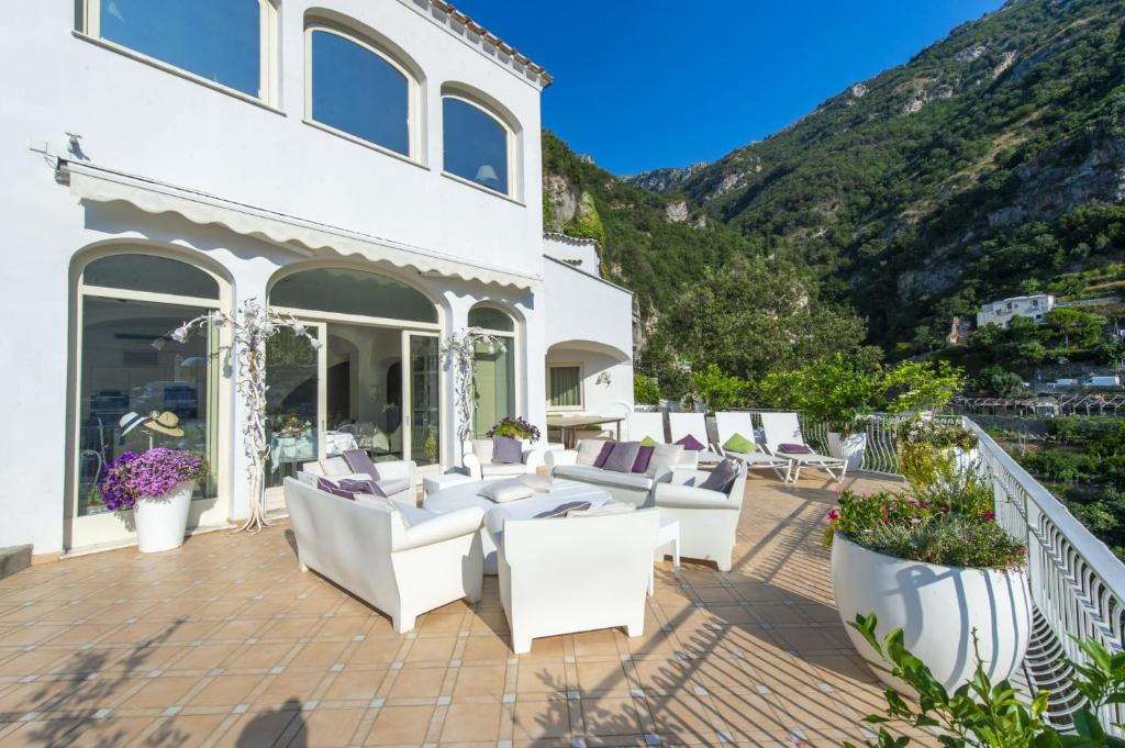 a patio with white furniture and a mountain at Villa Il Canto - Homelike Villas in Positano