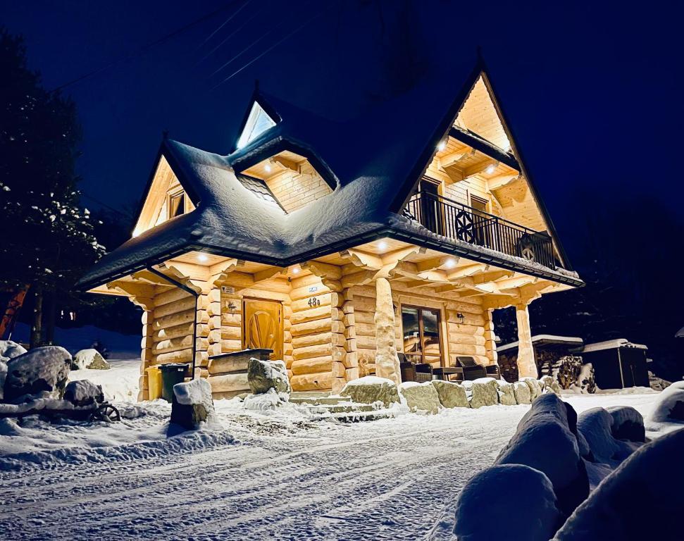 a log cabin with a blue roof in the snow at Góralska Chatka in Kościelisko