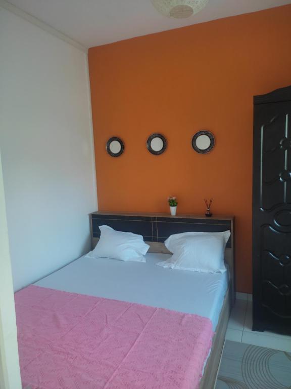 a bedroom with a bed with an orange wall at Le Jasmin Mamoudzou in Mamoudzou