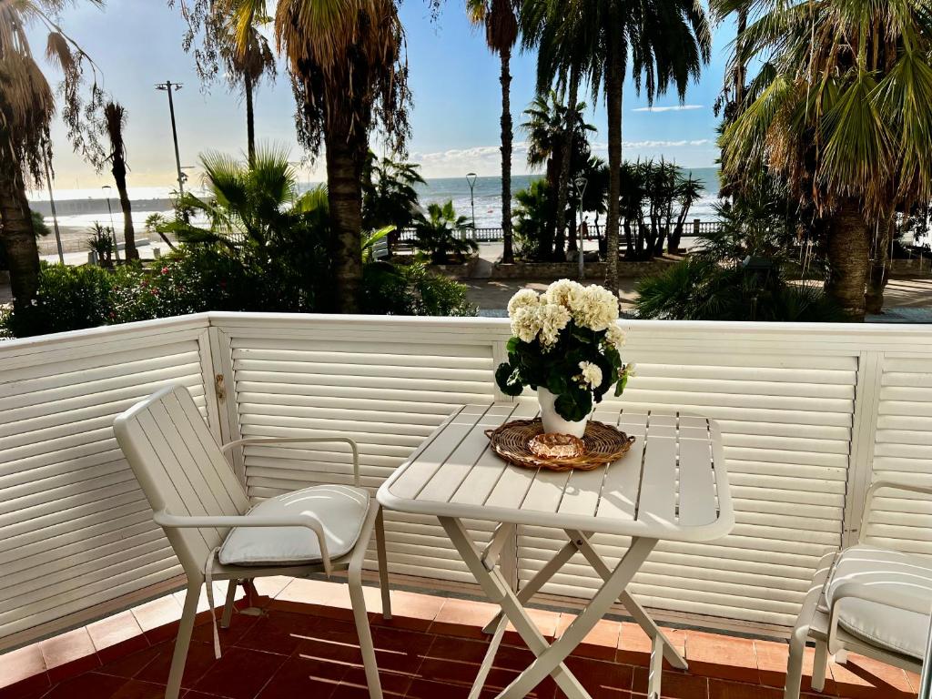 una mesa blanca y sillas con un jarrón de flores en Sitges Seafront Ribera Apartment, en Sitges