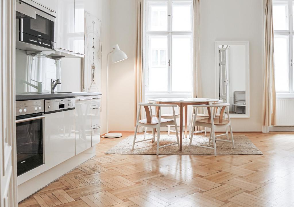 een witte keuken met een tafel en stoelen bij HeyMi Apartments Stephansdom in Wenen