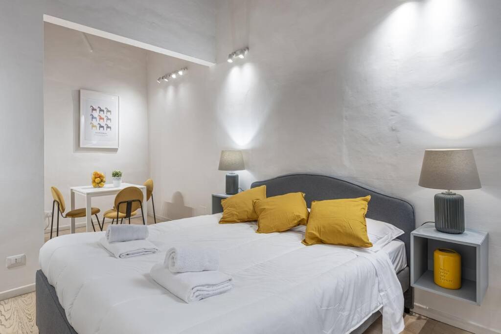 een slaapkamer met een groot wit bed met gele kussens bij UNYCA - Art of Florence Apartment in Florence