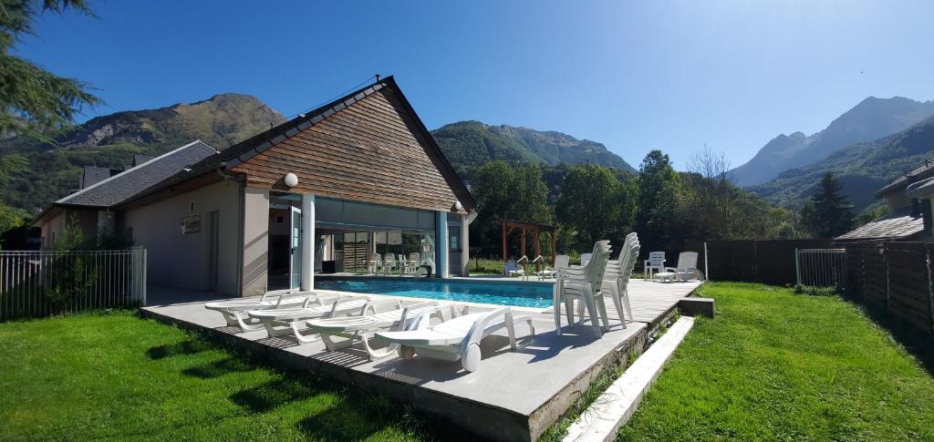 - un groupe de chaises blanches et une piscine dans l'établissement Résidence Val de Roland, à Luz-Saint-Sauveur