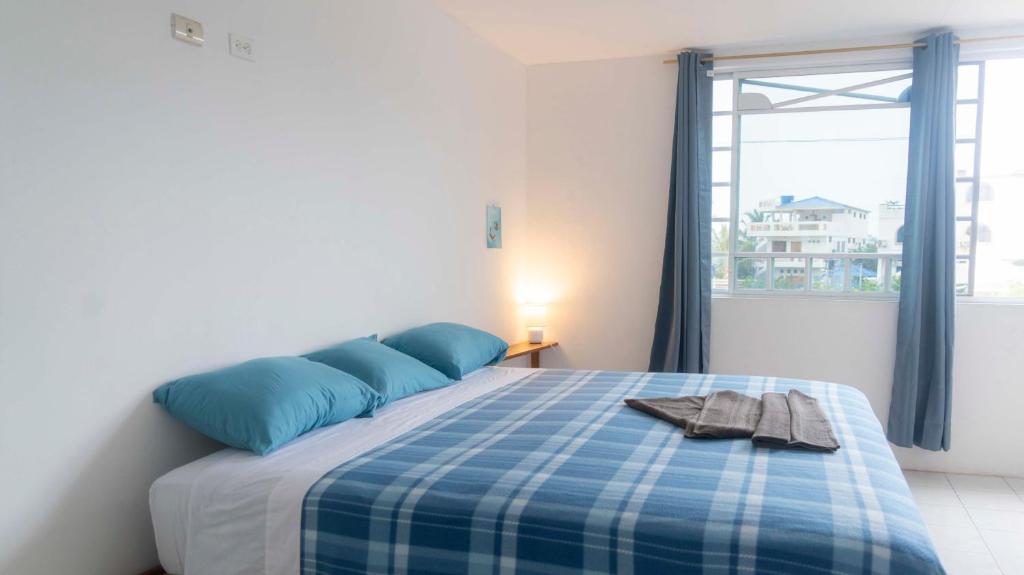 Un dormitorio con una cama azul y blanca y una ventana en My place in paradise, en San Cristobal