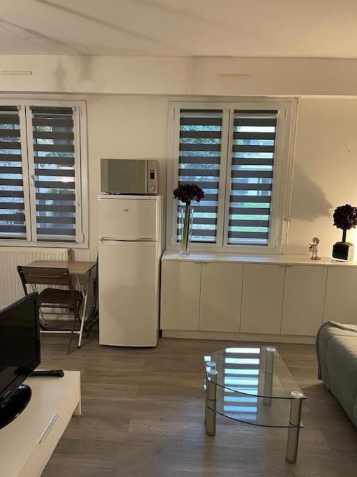 a living room with a white refrigerator and a table at Mytripinparis - Sablons in Neuilly-sur-Seine