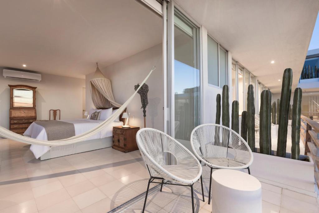 Un dormitorio con una hamaca y sillas. en Hotel Boutique Casa Lulu, en Mazatlán
