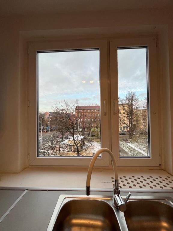 a kitchen window with a sink and a view of a city at BEMA Guest House - City Centre in Wrocław
