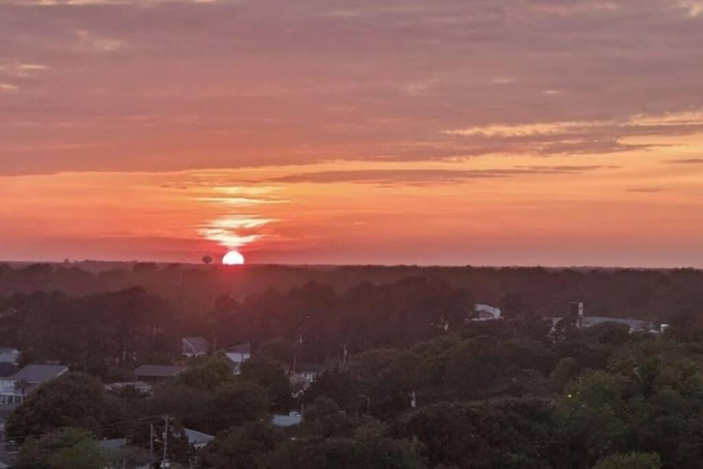 a sunset with the sun setting over a city at Oceanfront Get Away in Myrtle Beach