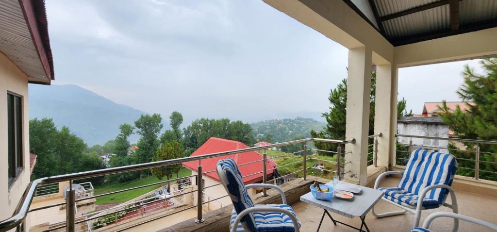 2 Stühle und ein Tisch auf einem Balkon mit Aussicht in der Unterkunft Haven Lodge Bhurban, 6BR Holiday Home in Hill Station in Bhurban