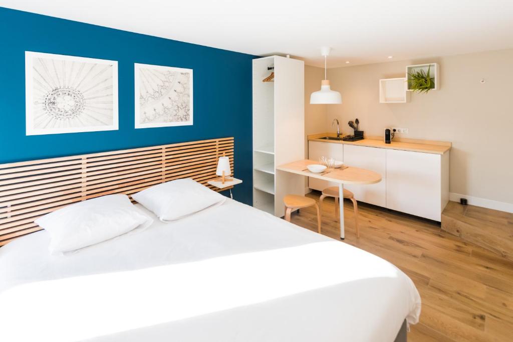 - une chambre avec un lit blanc et un mur bleu dans l'établissement Studios de la Nuée Bleue, à Strasbourg